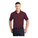 A man wearing a maroon Sport-Tek short sleeve polo shirt.