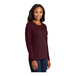 A woman wearing a Port & Company long sleeve maroon T-shirt.