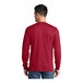 A man wearing a red Port & Company long sleeve shirt.