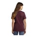 A woman wearing a maroon Port & Company short sleeve t-shirt.