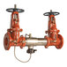 A close-up of a Watts reduced pressure zone assembly with OS&Y shutoff valves showing a pair of red handles.