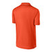 A back view of a deep orange Sport-Tek polo shirt.