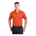 A man wearing a deep orange Sport-Tek polo shirt.
