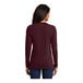 A woman wearing a maroon Port & Company long sleeve T-shirt.