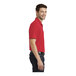 A close-up of a man's arm wearing a rich red Port Authority polo shirt.