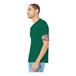 A man wearing a Bella + Canvas heather grass green t-shirt and jeans.
