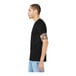 A man with tattoos on his arm wearing a black Bella + Canvas short sleeve t-shirt.
