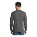 A man wearing a large charcoal Port & Company long sleeve t-shirt.