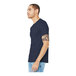 A man in a Bella + Canvas heather midnight navy blue shirt and jeans with a tattoo on his arm.