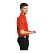 A man wearing a medium Port Authority® orange short sleeve polo shirt.