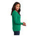 A woman wearing a green Port & Company long sleeve T-shirt.