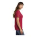 A woman wearing a red Port & Company short sleeve t-shirt with a pocket.