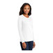 A woman wearing a white Port & Company long sleeve t-shirt.