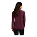 A woman with long brown hair wearing a burgundy long sleeve Port Authority polo shirt.