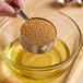 A person holding a measuring cup of brown powder labeled Wholesome Sweeteners Natural Sucanat Sugar.