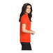 A woman wearing a Port Authority neon orange polo shirt.