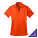 A small women's neon orange Port Authority polo shirt with a logo on it.