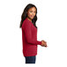 A woman wearing a red Port & Company long sleeve t-shirt.