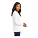A woman wearing a white Port & Company long sleeve t-shirt.