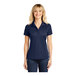 A woman wearing a navy Sport-Tek polo shirt with a collar.