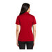 A woman wearing a red Port Authority Silk Touch polo shirt.