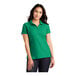 A woman wearing a bright kelly green Port Authority polo shirt.