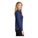 A woman wearing a Port Authority royal blue long sleeve polo shirt.
