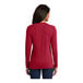 A woman wearing a Port & Company red long sleeve shirt.