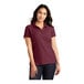 A woman wearing a Port Authority burgundy short sleeve pique polo shirt.