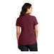 A woman wearing a burgundy Port Authority short sleeve polo shirt.