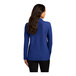 A woman with long hair wearing a royal blue Port Authority long sleeve polo shirt.