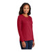 A woman wearing a red Port & Company long sleeve T-shirt.