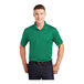 A man wearing a kelly green Sport-Tek moisture-wicking polo shirt.