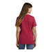 A woman wearing a red Port & Company short sleeve t-shirt.