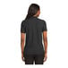 A woman wearing a black Port Authority polo shirt.