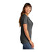 A woman wearing a dark heather grey Port & Company t-shirt.