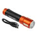 A close up of a black and orange Klein Tools Rechargeable LED Flashlight with a black USB cable attached.