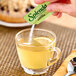 A hand pouring Splenda stevia into a glass of tea.