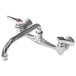 A chrome Advance Tabco wall mount swing faucet with two handles and two faucets.