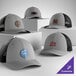 A customizable heather gray and black 6-panel trucker cap with a mesh back and structured, low profile design.