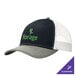 A black and white Port Authority trucker cap with a white and green logo on the front and a white mesh back.