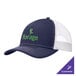A navy and white Port Authority trucker cap with a white mesh back and white and green text that says "forge"