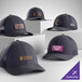 A collection of customizable heather navy and navy 6-panel trucker caps with mesh backs, featuring various logo designs on the front.