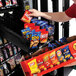 A person putting a bag of chips into a Selectivend snack vending machine.