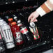 A hand putting a bottle of soda in a vending machine.