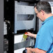 A man using a VEND MACH CD 10 SLT MECH & VAL machine to get a bottle from a refrigerator.