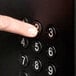 A finger pressing a black button with a number on a vending machine keypad.