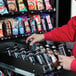 A man opening a VEND MACH SLT COMBO to take a beverage.