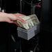 A person using a stack of money to pay for snacks from a vending machine.