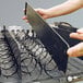 A person holding a metal tray with wires.